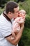 Portrait of young happy man holding his newborn cute babe dressed in white clothing. father embracing tenderly his adorable