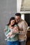 Portrait of young happy man and woman holding newborn cute babe dressed in white unisex clothing.