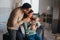 Portrait of young happy man and woman holding newborn cute babe dressed in white unisex clothing.