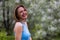 Portrait of young happy woman of thirty plus years old on a blurred background of flowering trees. Copyspace for text