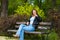 Portrait of a young happy woman of thirty plus years old having a rest in a park sitting on a bench. Copy space