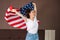 Portrait of a young happy woman waves an American flag. Indoor. The concept of the American national holidays and patriotism