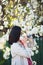 Portrait of young hidden woman in white blooming cherry branches in spring outdoor