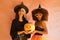 Portrait of young Hispanic and Latina women dressed as a witch smiling, sticking out a tongue and holding a pumpkin on a pink