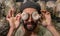 Portrait of young hispanic man holding oyster mushroom in front of his eyes.