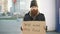 Portrait of young homeless man with cardboard looking at camera and wants to work for food looking at camera at street