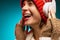 Portrait of young hsppy girl listening to cheerful music in white headphones isolated over blue background