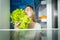 Portrait of young hungry woman looking inside of refrigerator and taking fresh healthy lettuce