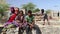 Portrait of young Indian girls and a boy, with man digging sand in background.