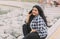 Portrait of a young Indian woman talking on the phone, sitting on the embankment.