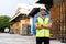 Portrait of young Indian worker with arm folded working in logistic industry in front of factory warehouse. Smiling