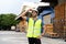 Portrait of young Indian worker working in logistic industry outdoor in front of factory warehouse. Smiling happy man