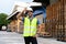 Portrait of young Indian worker working in logistic industry outdoor in front of factory warehouse. Smiling happy man