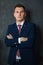 Portrait of young intelligent man lawyer standing with crossed arms in modern office building interior, successful male bank