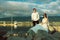 Portrait of young just married couple in wedding gowns and stylish sunglasses on the rock at the seaside