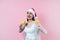 Portrait of young latin woman holding maracas rattle with copy space in a christmas concept on pink background