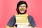 Portrait of young laughing man, holding bunch of books, wearing round eyeglasses on background of coral pink color.