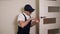 Portrait of young locksmith workman in blue uniform installing door knob.