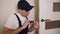 Portrait of young locksmith workman in blue uniform installing door knob.