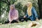 Portrait of young lovely pleasant mix ethnic woman sitting on grass at summer green park and having a discussion