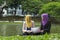 Portrait of young lovely pleasant mix ethnic woman sitting on grass at summer green park and having a discussion