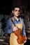 Portrait of a young luthier with a handcrafted violin in his workshop with the tools.