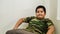 Portrait of young Malay boy with soldier shirt relaxing on a chair like a big boss at the living room.