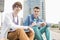 Portrait of young male college students studying on steps against building