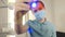 Portrait of young male dentist aiming and pointing flickering flashlight direct to camera with curing light. Close-up of