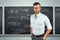 Portrait of a young male teacher on the background of the school blackboard. Teacher`s Day Knowledge Day back to school study