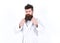 Portrait of a young man in bathrobe isolated on white background. Macho adjusting collar of his robe. Bearded guy in