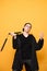 Portrait of a young man in black clothes trains with nunchakus on a yellow background and looks at the camera. Serious fighter