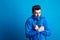 Portrait of a young man with blue anorak in a studio, feeling cold. Copy space.