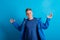 Portrait of a young man with blue anorak in a studio, standing against blue background.