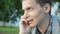 Portrait of young man calmly talking on phone. Summer day. Communication