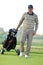 Portrait of young man carrying trolley with golf bag