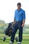 Portrait of young man carrying trolley with golf bag