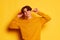 Portrait of young man with curly hair cheerfully posing with chilli pepper isolated over yellow background