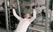 Portrait of a young man doing physical exercises, with a tense face training with a barbell sitting on a bench in the