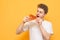 Portrait of a young man eating a piece of fresh tasty pizza on a yellow background. Hungry guy with a piece of pizza in his hands