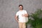 Portrait of young man with eco bag at indoor palm plant near grey