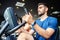 Portrait of young man exercising using stationary bike in gym with a group of people. Fitness class doing sport biking in the gym