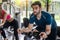 Portrait of young man exercising using stationery bike in gym with a group of people. Fitness class doing sport biking in the gym