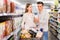 Portrait of young man with girlfriend choosing dairy products in supermarket
