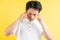 Portrait of young man having a headache on a yellow background