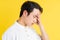 Portrait of young man having a headache on a yellow background