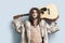 Portrait of young man holding guitar behind back against light blue background