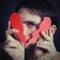 Portrait of a young man holding a paper broken heart