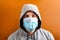 Portrait of young man in hood wearing protective medical mask with pandemic text at brown background. concept.