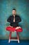 Portrait of a young man, lotus posture, red chair